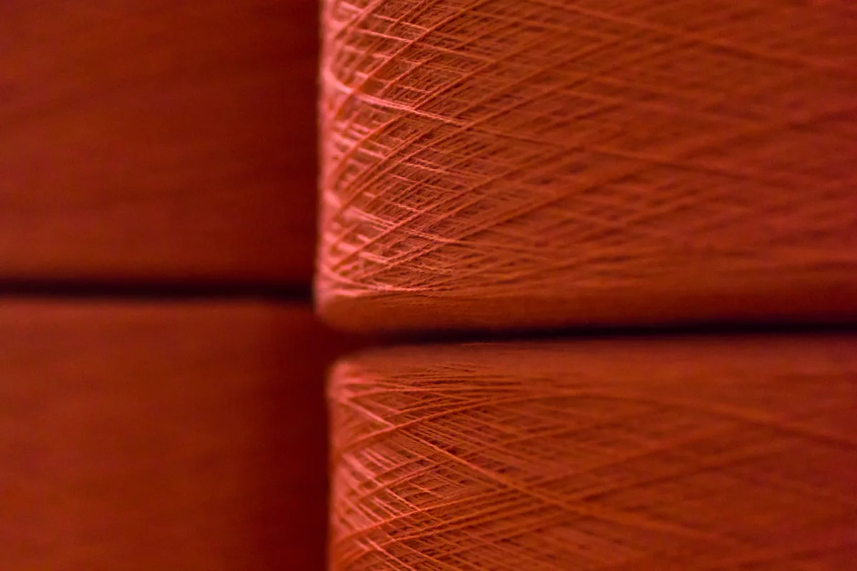 Detalhe da textura e do enrolamento de cones de fio em tom alaranjado